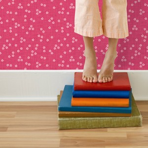 Girl standing on tiptoes on stack of books